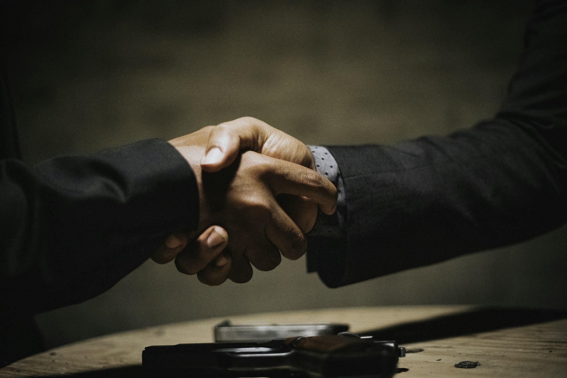 Two people shaking hands over a wooden table