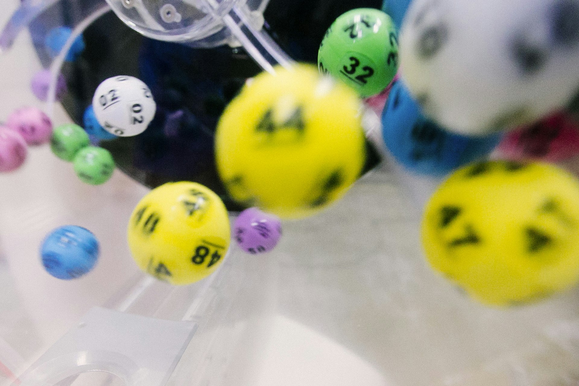 Colorful numbered lottery balls tumbling inside a clear mixing drum